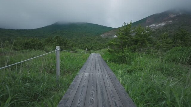 雨が降り出しそうな空の下で木道を歩く