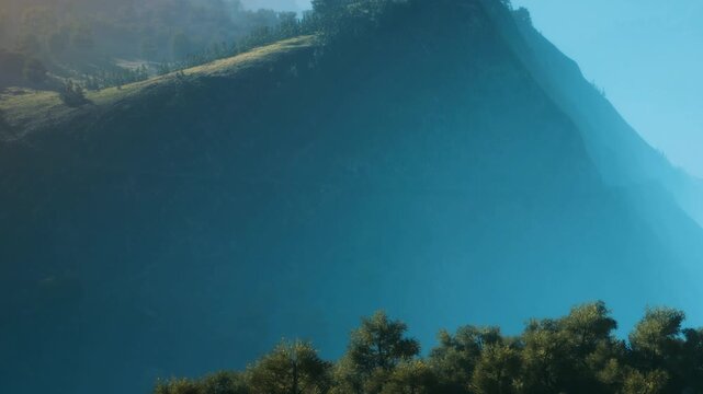 A mountain stands tall with greenery at its base under a clear blue sky. The light shines on the landscape, highlighting the shape of the mountain.