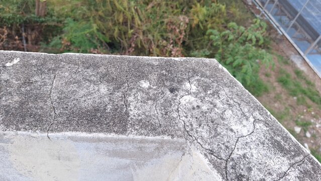 Weathered concrete wall edge with cracks and mold