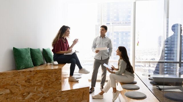 Group of diverse professional team members collaborating on corporate tasks, discussing project during meeting in coworking city office. Business communication, strategy planning, teamwork concept