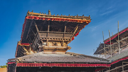 The multi-tiered roof of the pagoda against the blue sky. Latticed railings, Beautiful wood carvings, log beams.  Red frills along the edges of the cornices. Nepal. Kathmandu. Durbar Square. © Вера 