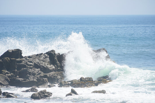 海岸の岩肌に激しくぶつかり白く立ち上る豪快な波しぶき