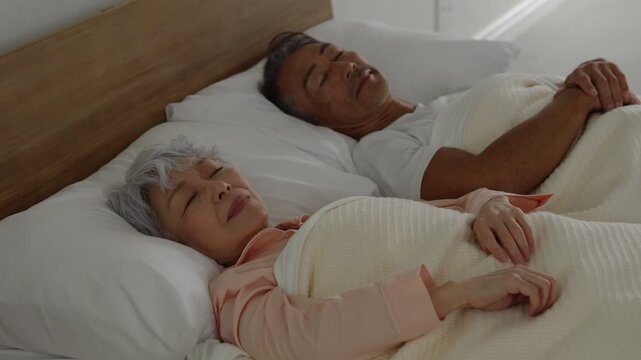 ベッドで寝るシニア夫婦