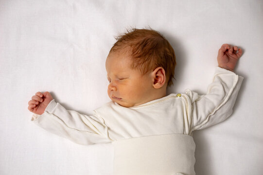 Tiny infant resting in deep slumber, showing innocence and tranquility against a simple white background, symbolizing new life and childhood