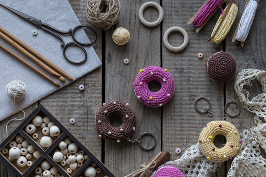 Sewing and knitting tools flat lay with donut pincushions embroidery hoop scissors yarn beads and lace on rustic wooden table cozy handmade craft background