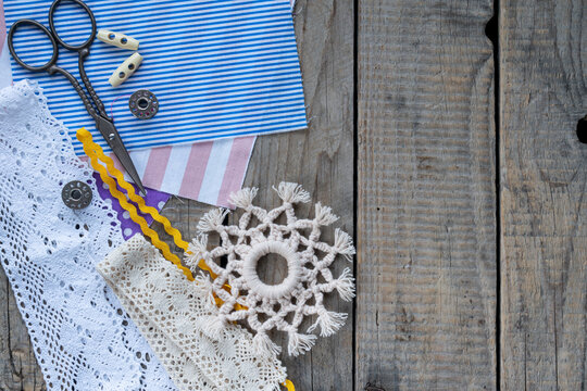 Handmade crochet snowflake ornament with lace colorful threads scissors and sewing accessories on rustic wooden background winter craft flat lay composition