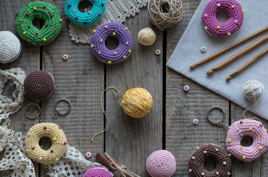 Handmade knitting and sewing frame composition with colorful donut pincushions yarn scissors lace and embroidery accessories on wooden table flat lay