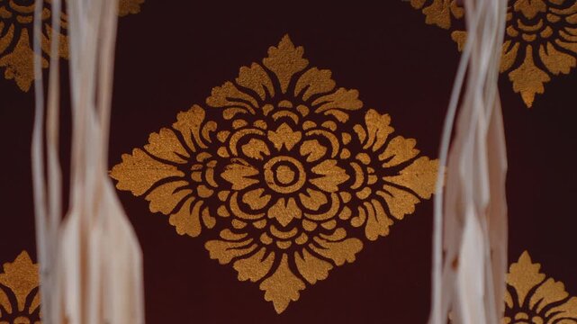 Traditional Balinese golden floral pattern decoration on a dark red background