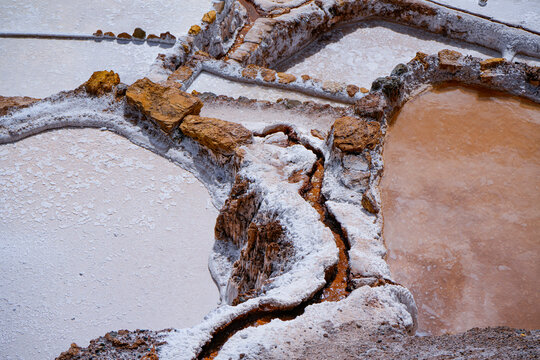 Aerial view of crystallized salt ponds beside an orange mineral water channel