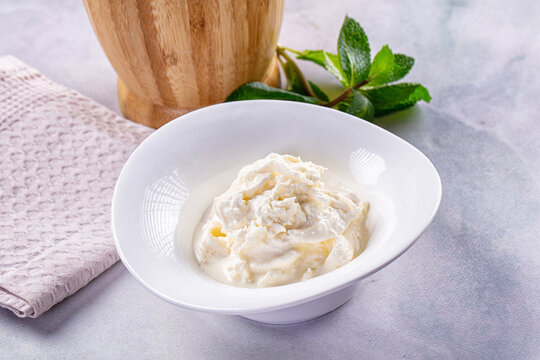 Creamy Italian stracciatella cheese in white bowl with fresh mint garnish