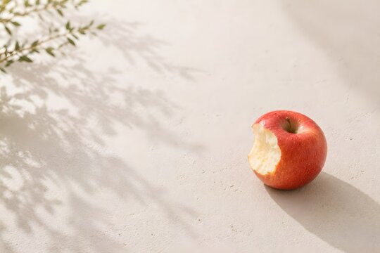 Bitten Red Apple on Soft Beige Background with Natural Window Light