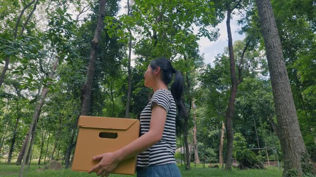 Asian woman holding recycling box on green nature forest background. Sustainable environment concept. Recycle plastic free of zero waste, from waste to environment.