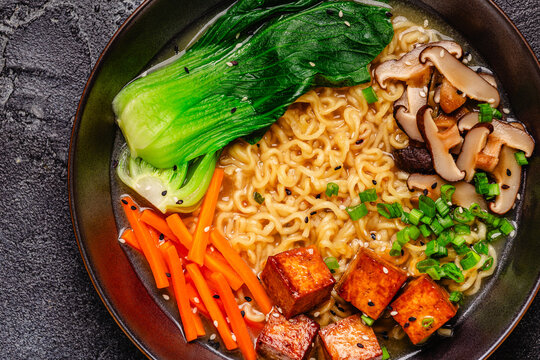 Noodles ramen miso soup served with tofu, bok choy, carrots, and mushrooms.