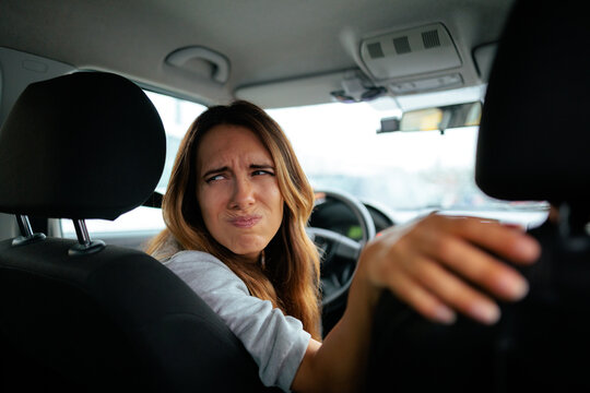 Focused Female Driver Squinting Eyes While Checking Behind For Reversing Car. Attentive woman chauffeur looking carefully backwards through window with narrowed gaze during reverse parking
  