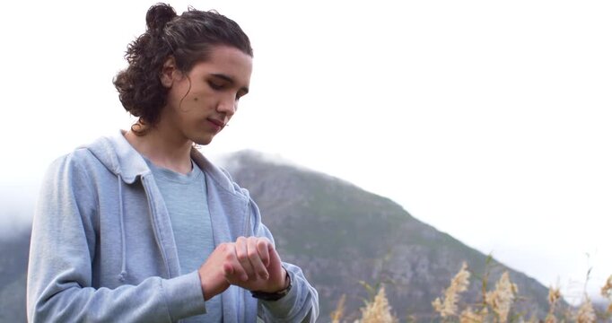 African American man checking buzzing smartwatch, adjusting hoodie and scanning mountain for route
