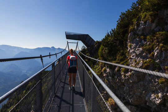 Woman with backpack walking on the spectacular suspension bridge on Hochkar mountain in Alps, Austria