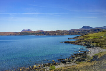 Fototapeta premium The picturesque coastal landscape of Gruinard Bay in the northwestern Highlands of Scotland, overlooking the blue, clear waters of the Atlantic Ocean and the dome-shaped hills in the background.