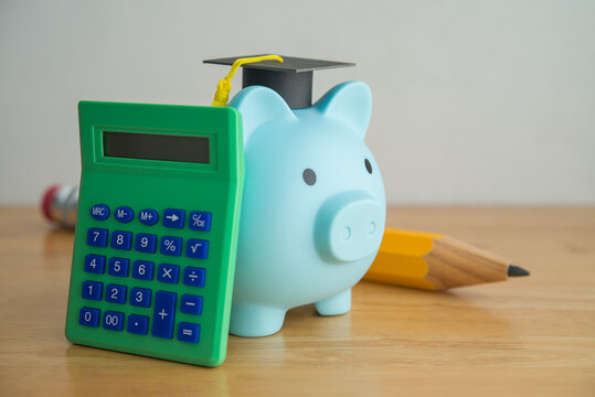 Piggy bank with mortarboard, calculator and pencil. Personal financial management for education, repayment student loan or debt, tuition, find out scholarship for studying abroad and so on concept.