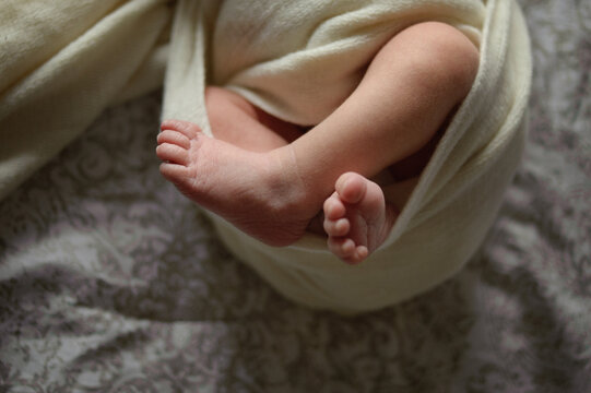 Close up of newborn baby feet poking out of a swaddle