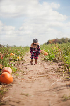 Young girl in a plaid coat at a pumpkin patch