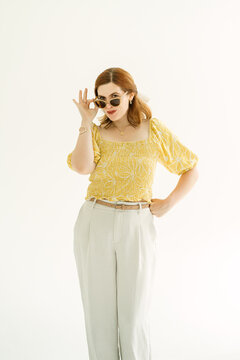 Confident redhead woman peering over her sunglasses