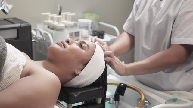 Japanese head spa therapist prepares a head wrap for a heated steaming cap for deep conditioning and scalp therapy during a luxury salon treatment at japanese head spa..