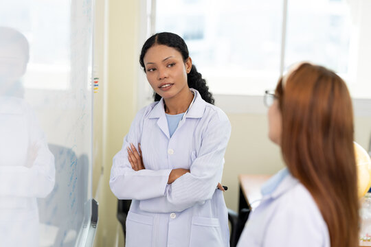 African American scientist writing on whiteboard in laboratory