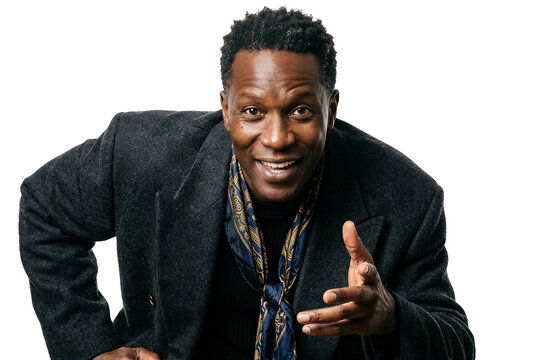 Man looks at camera while smiling and gestures with hand. Bright and simple background highlights his outfit. Concept of personal branding, fashion, marketing
