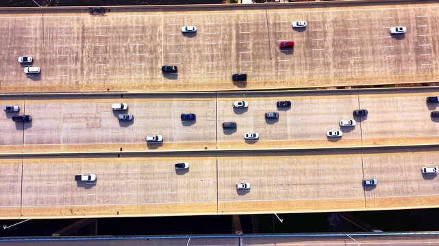 Top down view of traffic on three lane highway sections. Overhead drone image of cars and trucks spaced across concrete bridge deck lanes.