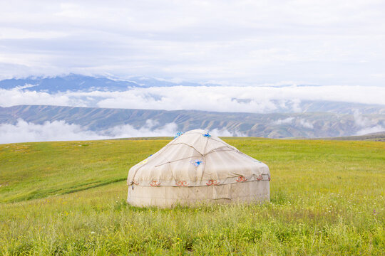 Mongolian yurts with distant mountains and sea of clouds on Nalati Grassland, Xinjiang, China