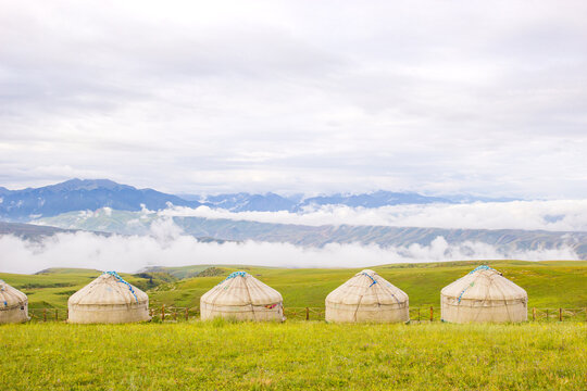 Mongolian yurts with distant mountains and sea of clouds on Nalati Grassland, Xinjiang, China