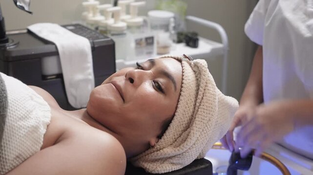 Japanese head spa therapist applying a warm facial towel wrap after scalp treatment for relaxation and post-spa comfort.