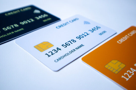 Macro angled diagonal sequence of black, white, and orange credit and debit cards on a white surface