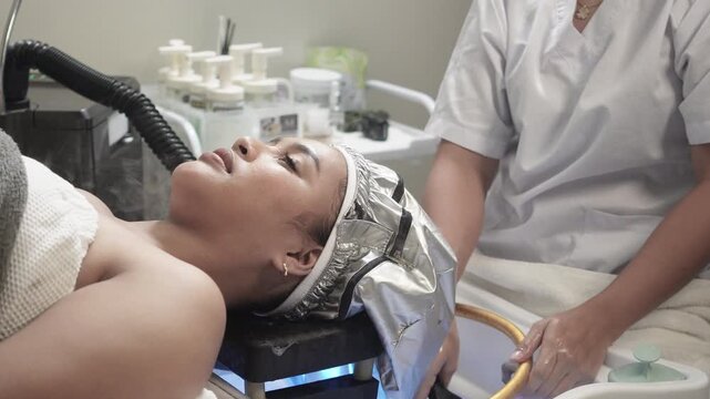 Client receiving a thermal steam cap deep conditioning treatment during a Japanese head spa session for scalp and hair rejuvenation.