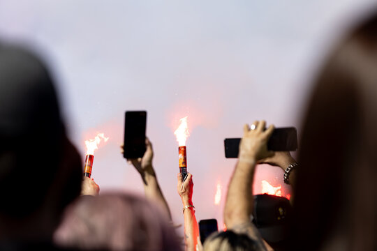 Hands hold burning torches and smartphones aloft