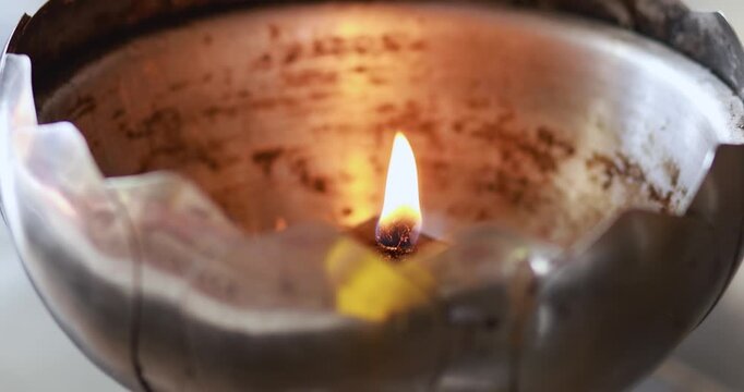 Oil lamp flame burning in a metal holder with a warm glow. Ideal for light, spirituality, tradition, meditation, hope, ceremony, and peaceful atmosphere concepts, close-up
