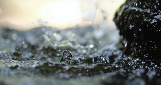 Water flowing from a fountain and splashing onto the surface, creating ripples and droplets, freshness and purity, tranquility, and nature. close-up