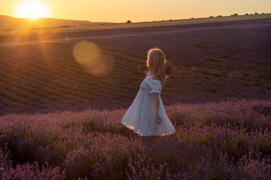 Lavender sunset woman standing in purple field holding flowers during golden hour tranquility