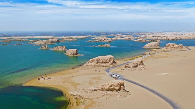 Aerial view of unique water yardang landforms surrounded by turquoise water and desert sand in Qinghai, China.