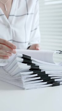 Accountant or financial professional reviewing business documents and calculating expenses on a white desk, managing taxes, financial records, and official paperwork for audit or reporting