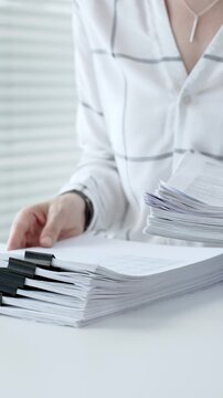 Accountant or financial professional reviewing business documents and calculating expenses on a white desk, managing taxes, financial records, and official paperwork for audit or reporting