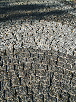 A close-up of gray granite pavers laid in a semicircular arc. A concept for a durable natural stone flooring solution.