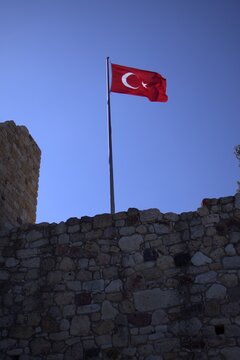 Waving Turkish Flag on Historic Castle Walls Against Clear Blue Sky