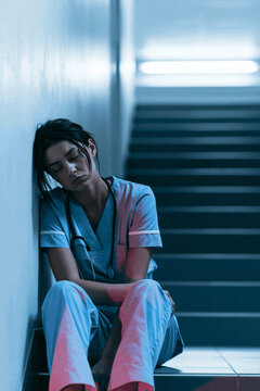 Exhausted nurse sitting alone in stairwell during break