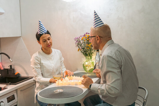 Birthday Couple Chess Game Kitchen: Celebrating anniversary indoors playing chess; birthday hats, candles.