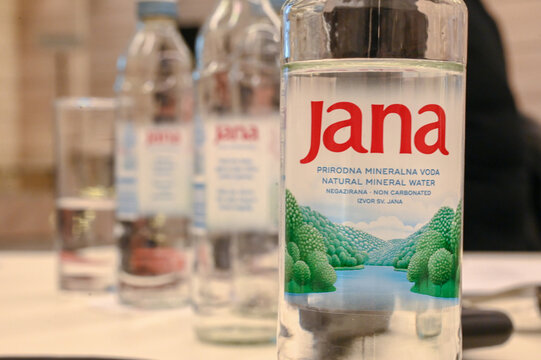 Jana bottled drinking water bottles in a row on table. Jana mineral water bottles on wooden table.