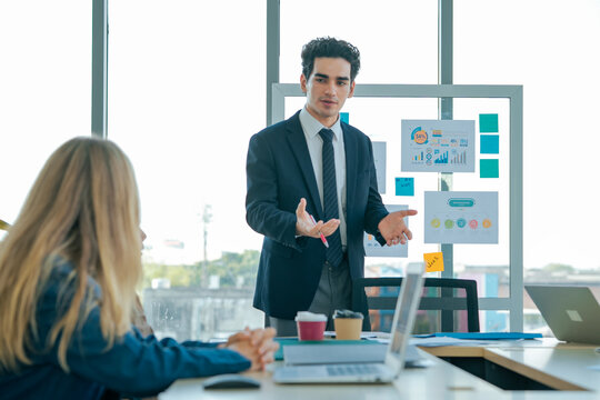 Professional speaker explains business presentation with clear strategy. Colleagues review analytics, compare statistics, discuss solutions, improve planning, strengthen teamwork, productivity.
