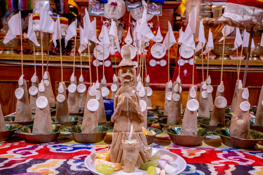 Kalachakra Temple, McLeod Ganj, Dharamsala, Himachal Pradesh, India. Clay offerings with white flags and fruit arranged on trays in a Buddhist temple.