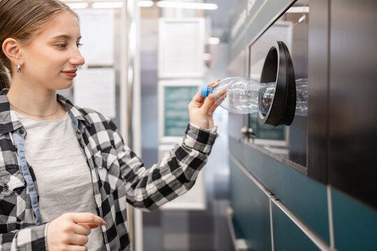 Girl Recycling Empty Plastic Bottles In Machine At Supermarket