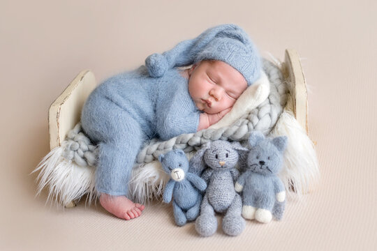 Newborn baby rests, wearing blue knitted romper. Tiny feet peek out. Professional newborn photoshoot.